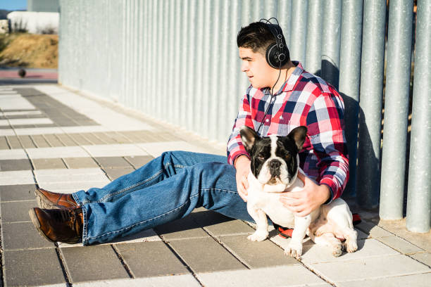 vista lateral de un joven escuchando música con un bulldog - tin can phone fotografías e imágenes de stock