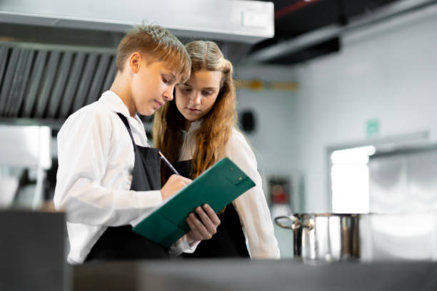 학생들은 표준 주방과 완벽한 장비를 갖춘 요리 연구소에서 요리하는 법을 배우고 있습니다. 그리고 전문 요리사를 트레이너로 삼으십시오. - chef trainee cooking teenager 뉴스 사진 이미지