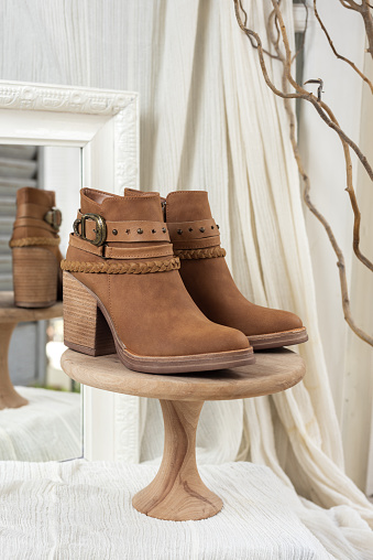 A vertical shot of beige suede female boots in a showroom