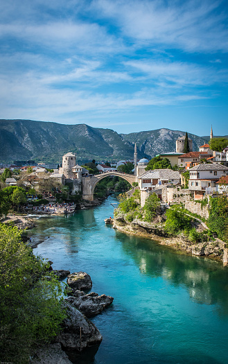 Hermosa vista de la ciudad de Mostar con mezquita, edificios antiguos y antiguo puente de arco en el río Neretva photo