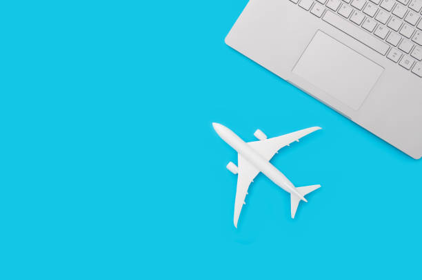 istock Small, white plane in front of a gray notebook with a blue background 1464083030