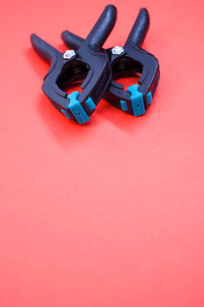istock Vertical shot of two plastic spring clamp tools isolated on red background 1464083422