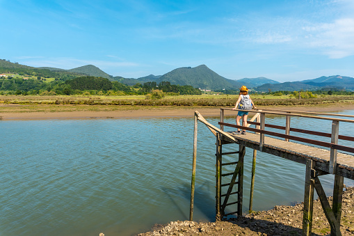 A young woman on the wooden piers of the Urdaibai marshes, a Bizkaia biosphere reserve next to Mundaka. Basque Country