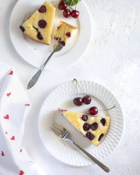 2 pieces of cherry cake on white plates and white background.