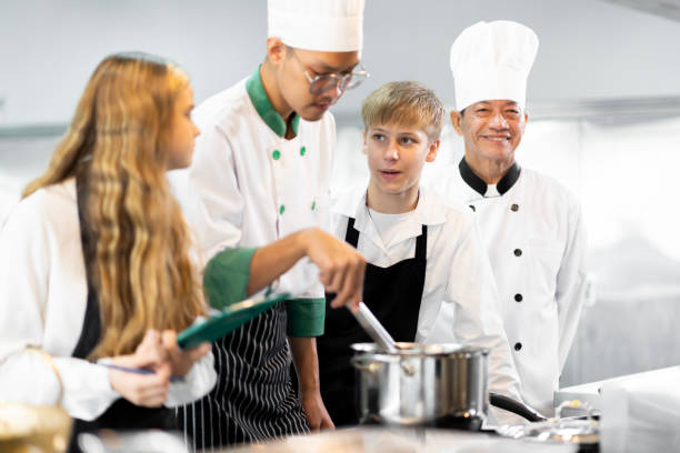 students are learning to cook in a culinary institute with a standard kitchen and complete equipment. and have a professional chef as a trainer. - chef trainee cooking teenager imagens e fotografias de stock