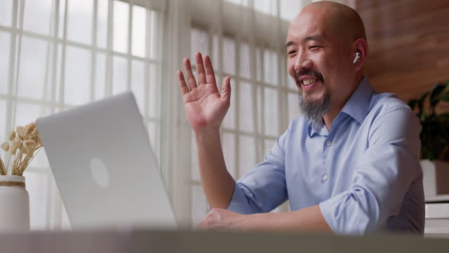 happy middle-aged businessman greets his colleagues through the computer