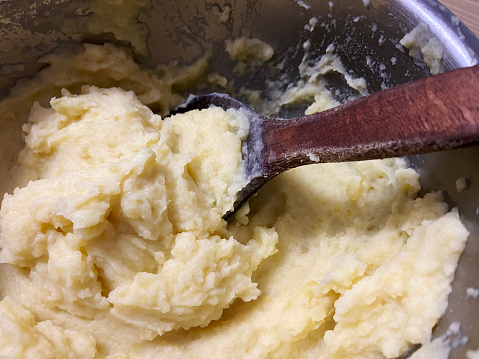 Mashed potatoes in a pot with wooden spoon
