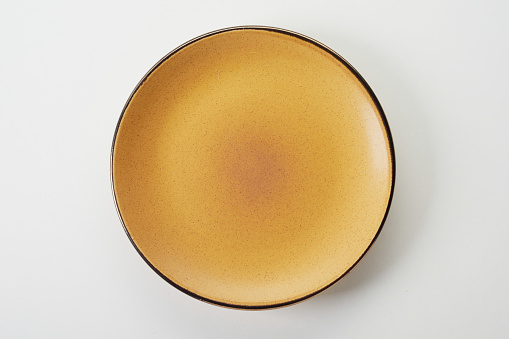 A top view of a yellow ceramic flat plate on a white background
