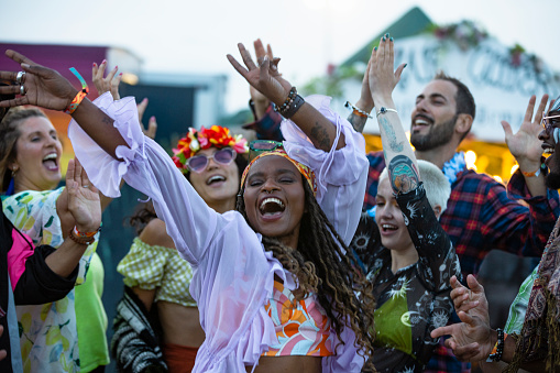 A small group of friends at a festival all dancing together and having a good time. Everyone is happy and smiling and sharing positive energy.