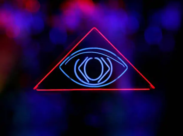 A selective focus shot of a neon Illuminati evil eye in a pyramid