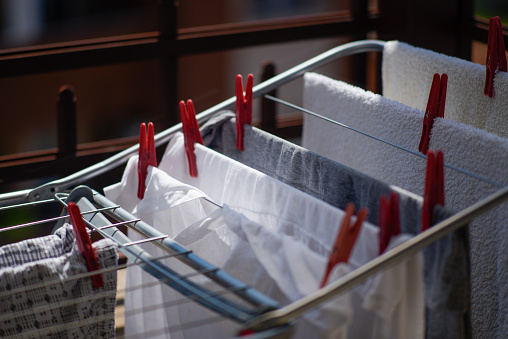 A close up of outspread clothes on indoor folding clothes with red close pins