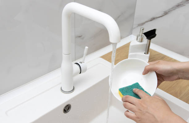 istock A girl washes a plate with a sponge in a white kitchen sink. 1464103961