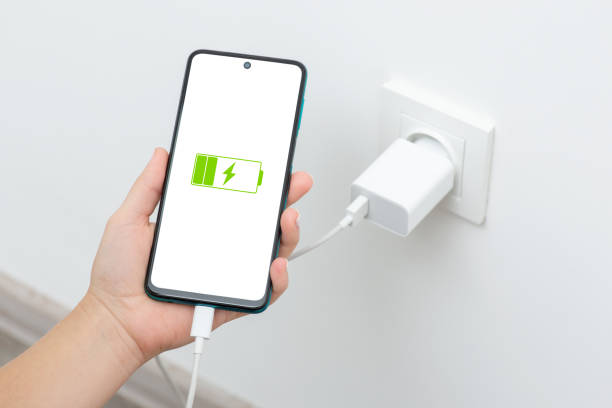 istock Female holding phone while charging from wall outlet 1464107722