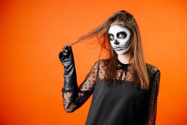 Scary female face with helloween horror grimm. Orange background. Scary female face with helloween horror grimm. Orange background. High quality photo grimma stock pictures, royalty-free photos & images