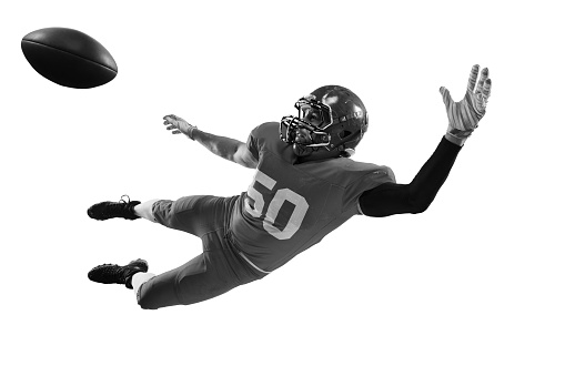 Monochrome portrait of professional american football player in sports uniform and protective helmet in motion isolated over white background. Concept of energy, sport, competition. Copy space for ad