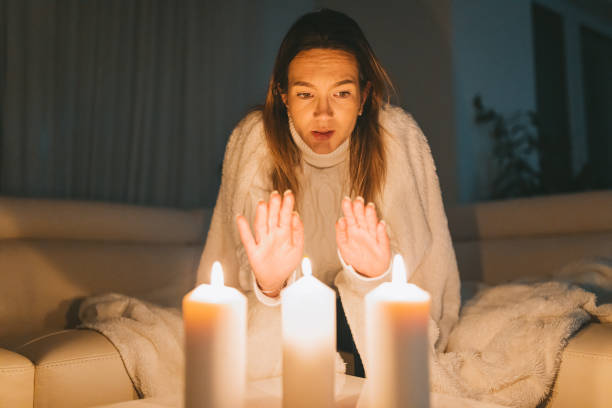 A woman who is cold because of a power cut tries to warm herself.