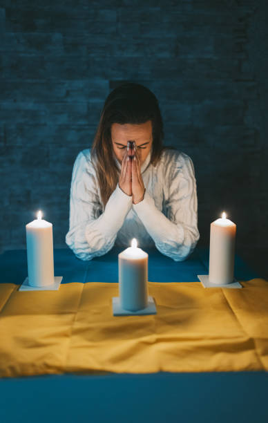 istock Devastated woman praying by candlelight 1464117140