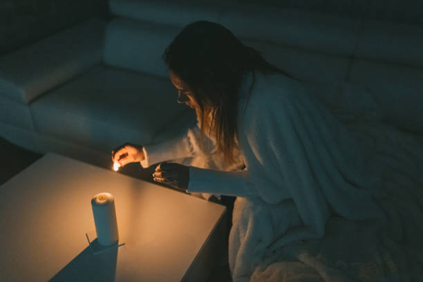 Woman lighting a match to light up the candle due to the current restriction.