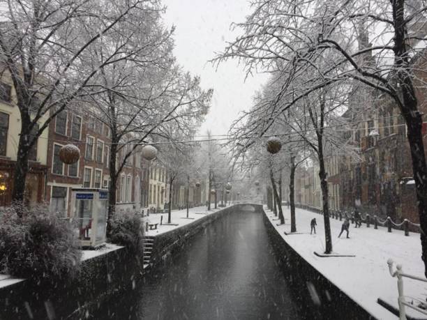 Delft canal in a snowy day Delft canal in a snowy and cold day,m in an empty and relaxing street delft winter netherlands snow stock pictures, royalty-free photos & images