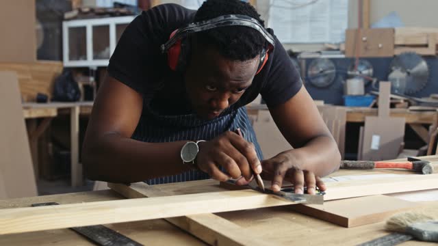 Young focused African carpenter measure his new deign project