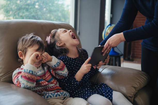 une mère interdit à sa fille et à son fils de jouer à des jeux sur une tablette numérique, concept de dépendance aux gadgets - enfant rebelle photos et images de collection