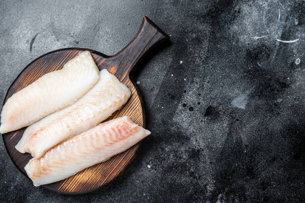 istock Fillets of codfish, raw cod fish meat. Black background. Top view. Copy space 1464120999