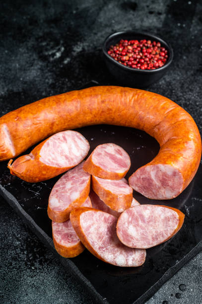 istock Smoked sausage on a marble board. Black background. Top view 1464123127