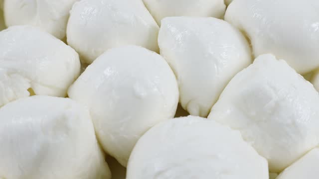 Many fresh white mozzarella cheese balls rotation close up
