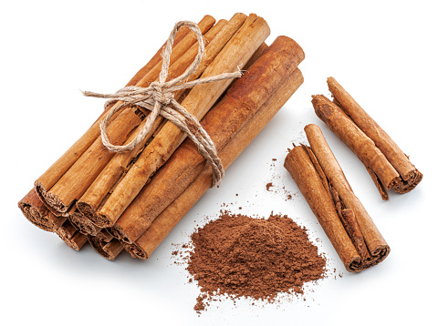 Cinnamon dried bark strips and cinnamon powder, sweet-smelling brown substance used in cooking, isolated on white background.