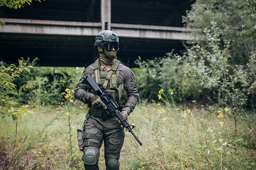 Military man standing ready for work in camouflage gear in training ground