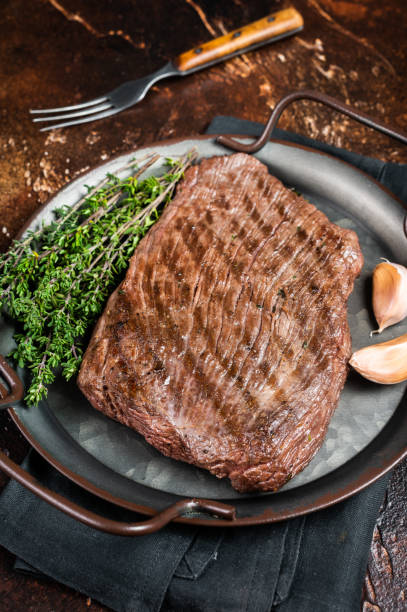 istock Grilled flank beef steak with herbs. Dark background. Top view 1464127053