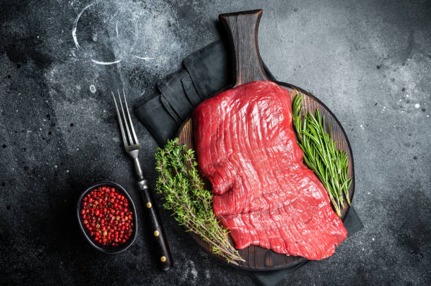 istock Raw flank beef steak, uncooked meat with herbs. Black background. Top view 1464127501