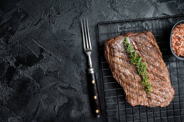 istock Roasted medium rare flank beef steak with thyme. Black background. Top view. Copy space 1464127757