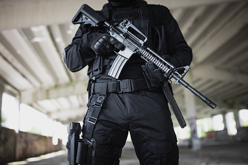 Close-up of a young man standing in special force gear with rifle gun
