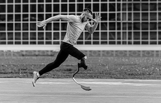 disabled athlete on prosthesis running black and white photo