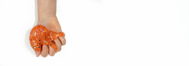 istock banner orange slime with sequins in child's hand white background 1464129441