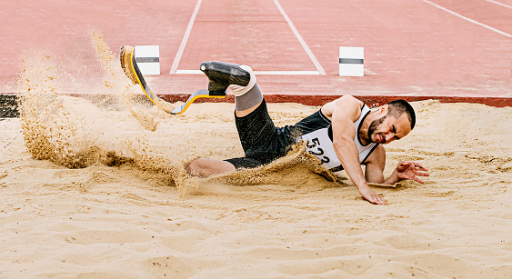disabled athlete landing sand in long jump