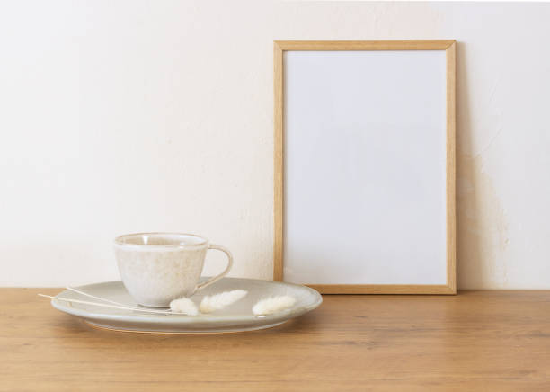 istock Horizontal white frame mockup on a vintage wooden bench, table, ceramic mug, and saucer with dry Lagurus ovatus grass. White wall background. Scandinavian interior. Selective focus. 1464130150