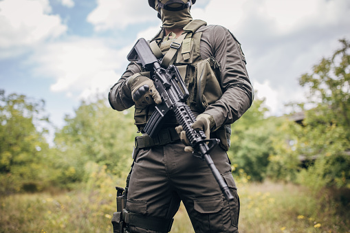 Military man standing ready for work in camouflage gear in forest