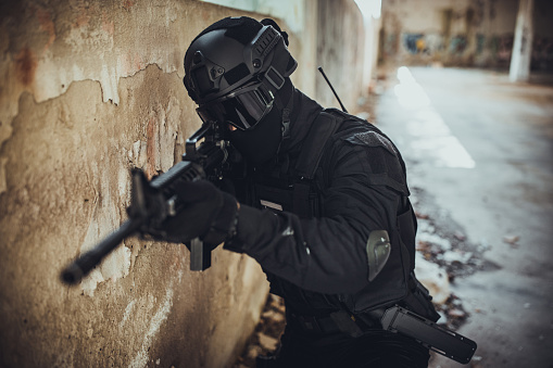 Young man aiming at something in special force gear with rifle gun