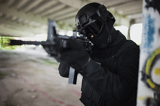 Young man aiming at something in special force gear with rifle gun