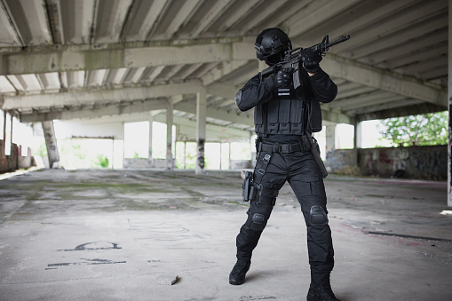 Young man aiming at something in special force gear with rifle gun