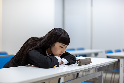 High school girl studying in classroom - tired