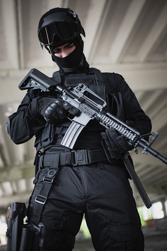 Young man standing in special force gear with rifle gun