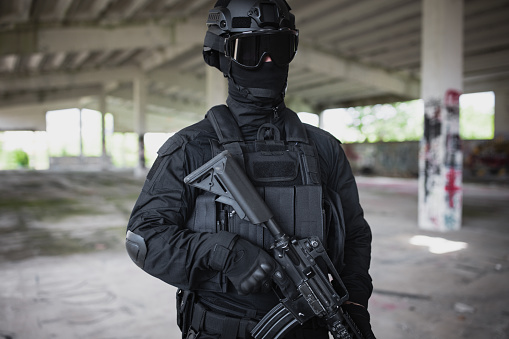 Young man standing in special force gear with rifle gun