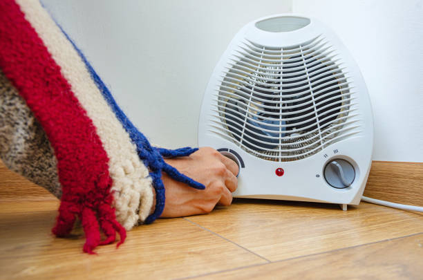 istock Woman's hand turns on electric heater 1464134275