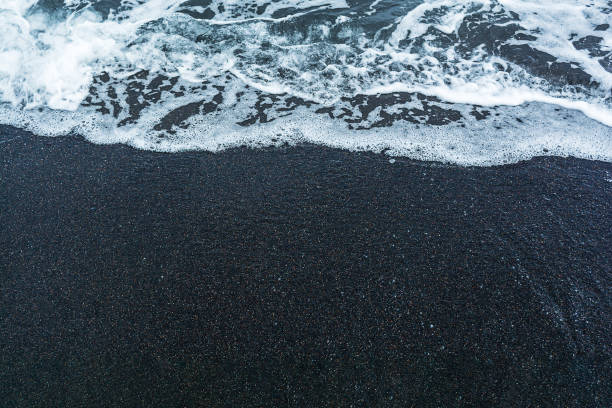 istock Black volcanic sand on the beach with waves. 1464135886