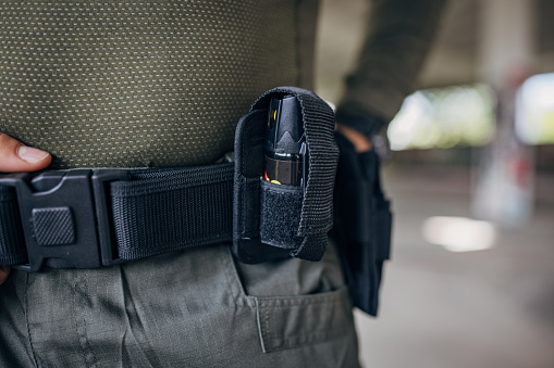 Close-up of a young man standing in tactical gear with belt on his hip and pepper spray holder