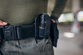 Close-up of a young man standing in tactical gear with pepper spray holder