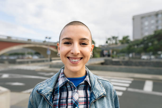 Shaved head girl smiling in front camera stock photo